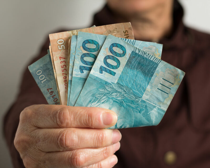 Paper notes from Brazil. Brazilian cash. Front view senior person holding bills.